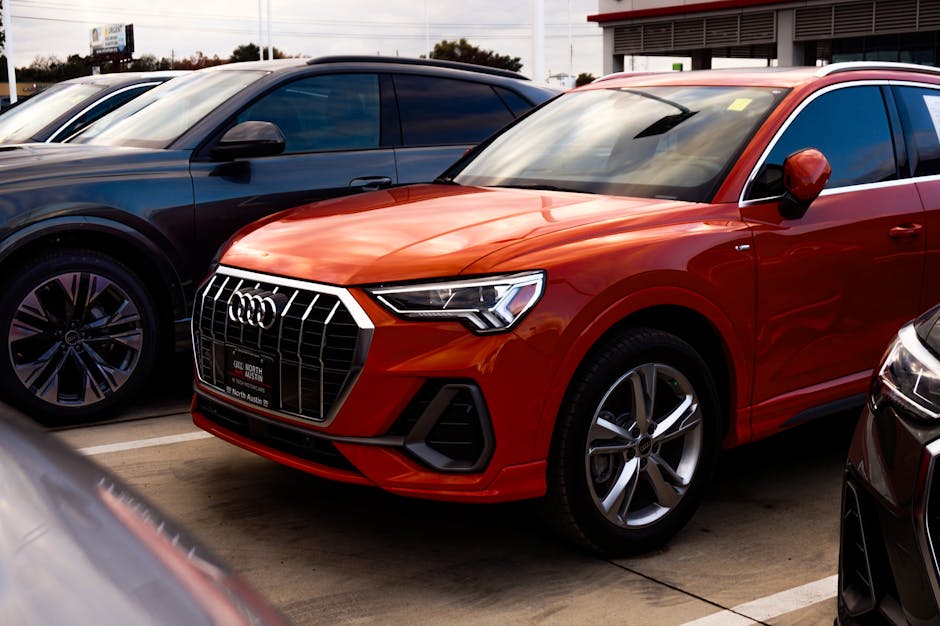 A vibrant orange SUV parked among other vehicles at a car dealership, showcasing modern car design