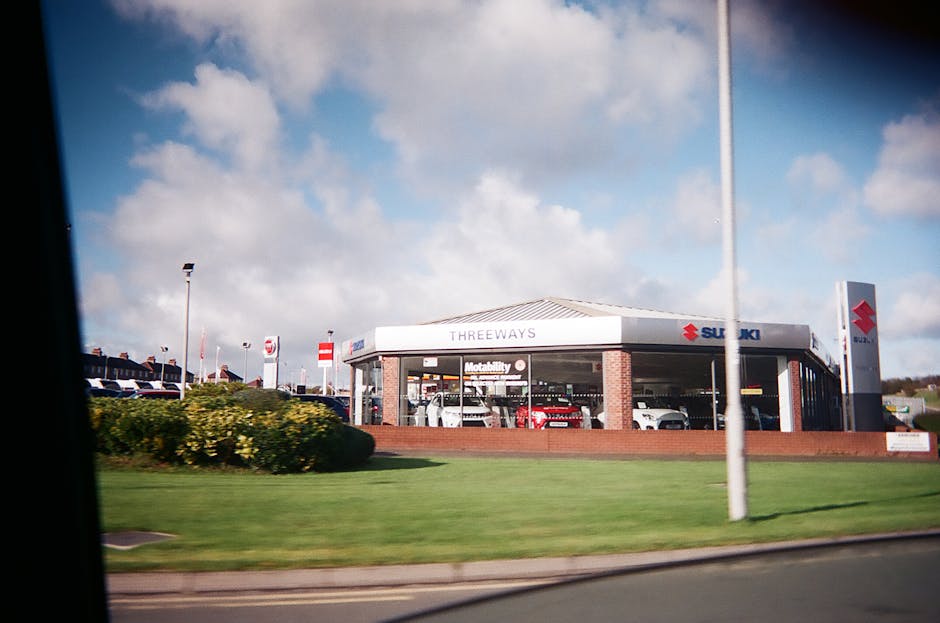 Exterior view of a car dealership featuring Suzuki automobiles under a bright sky